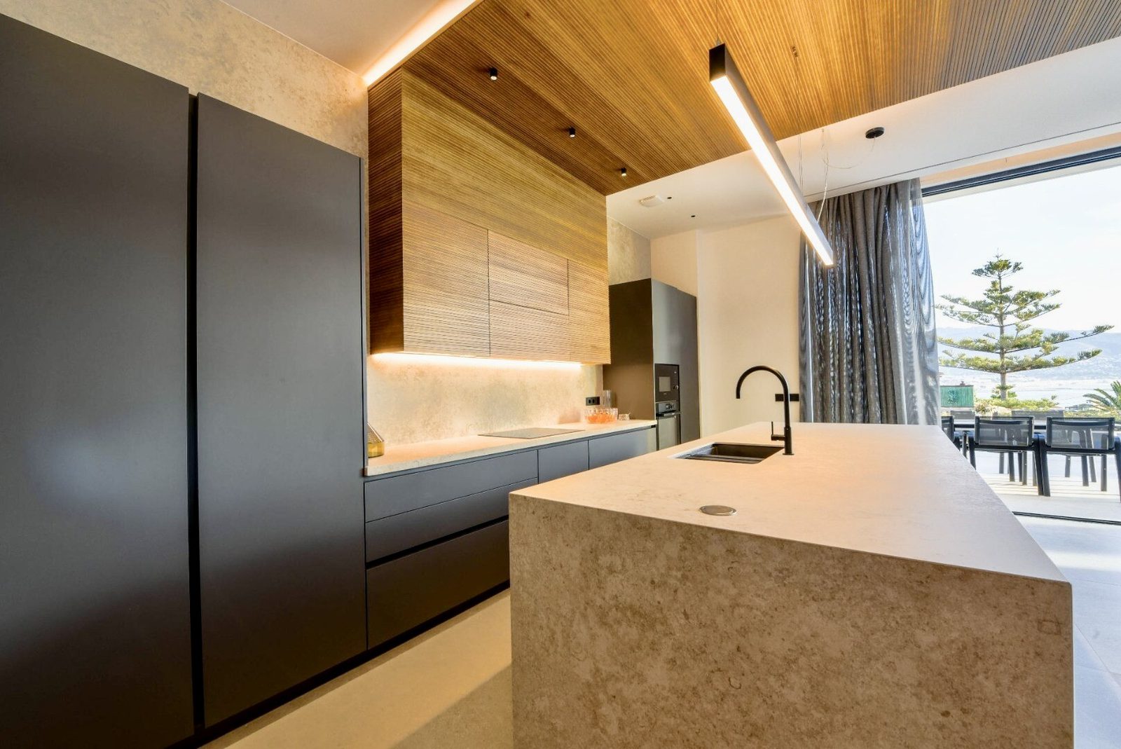 A modern kitchen with sleek cabinetry and a marble island in a 4-bedroom villa in La Nucia - The Estates
