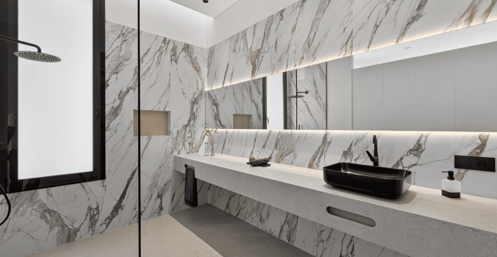 A modern, marble-clad bathroom with a sleek vanity and mirror in a 4-bedroom villa in La Nucia - The Estates