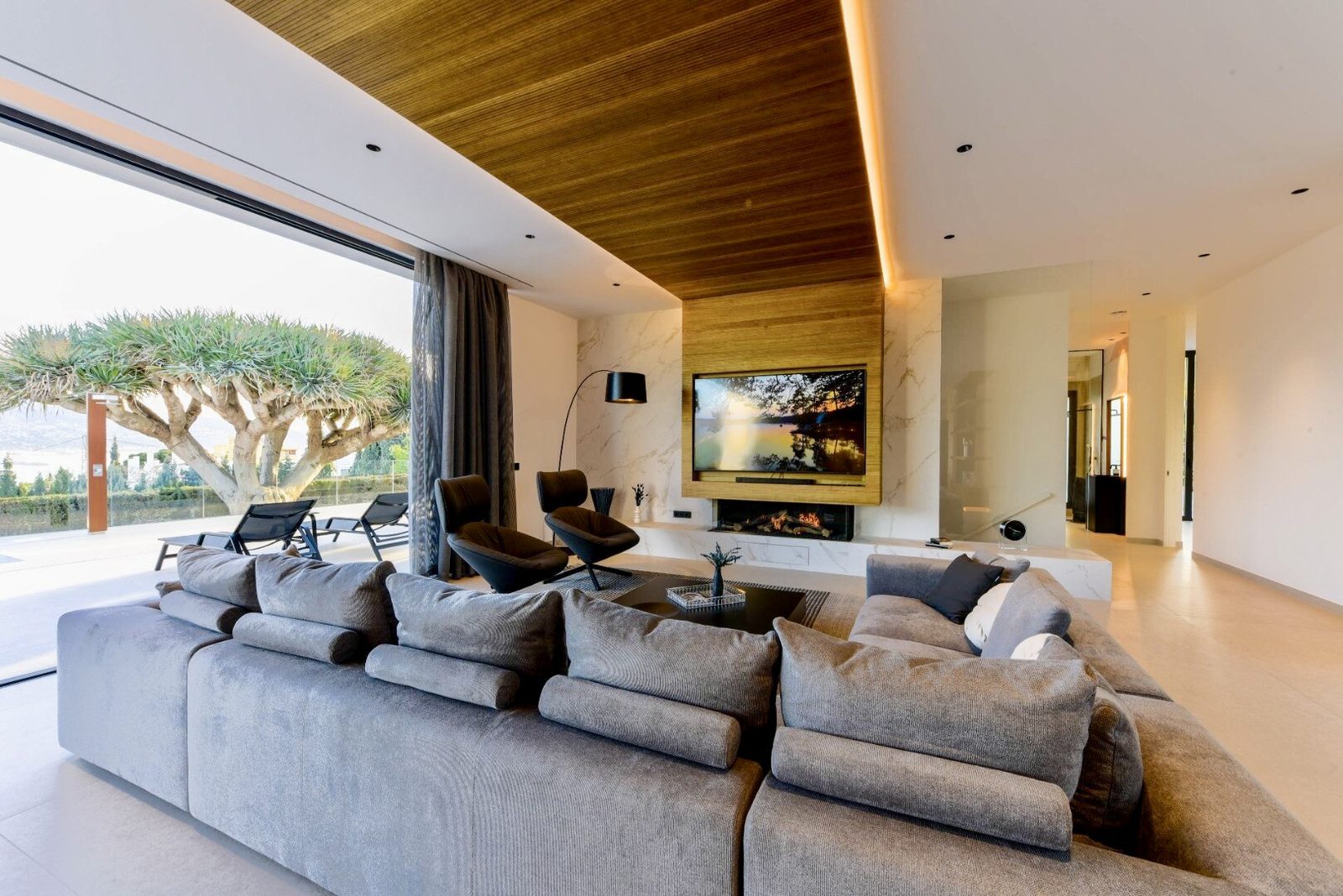 Stylish living room with a large sectional sofa and fireplace in a 4-bedroom villa in La Nucia - The Estates