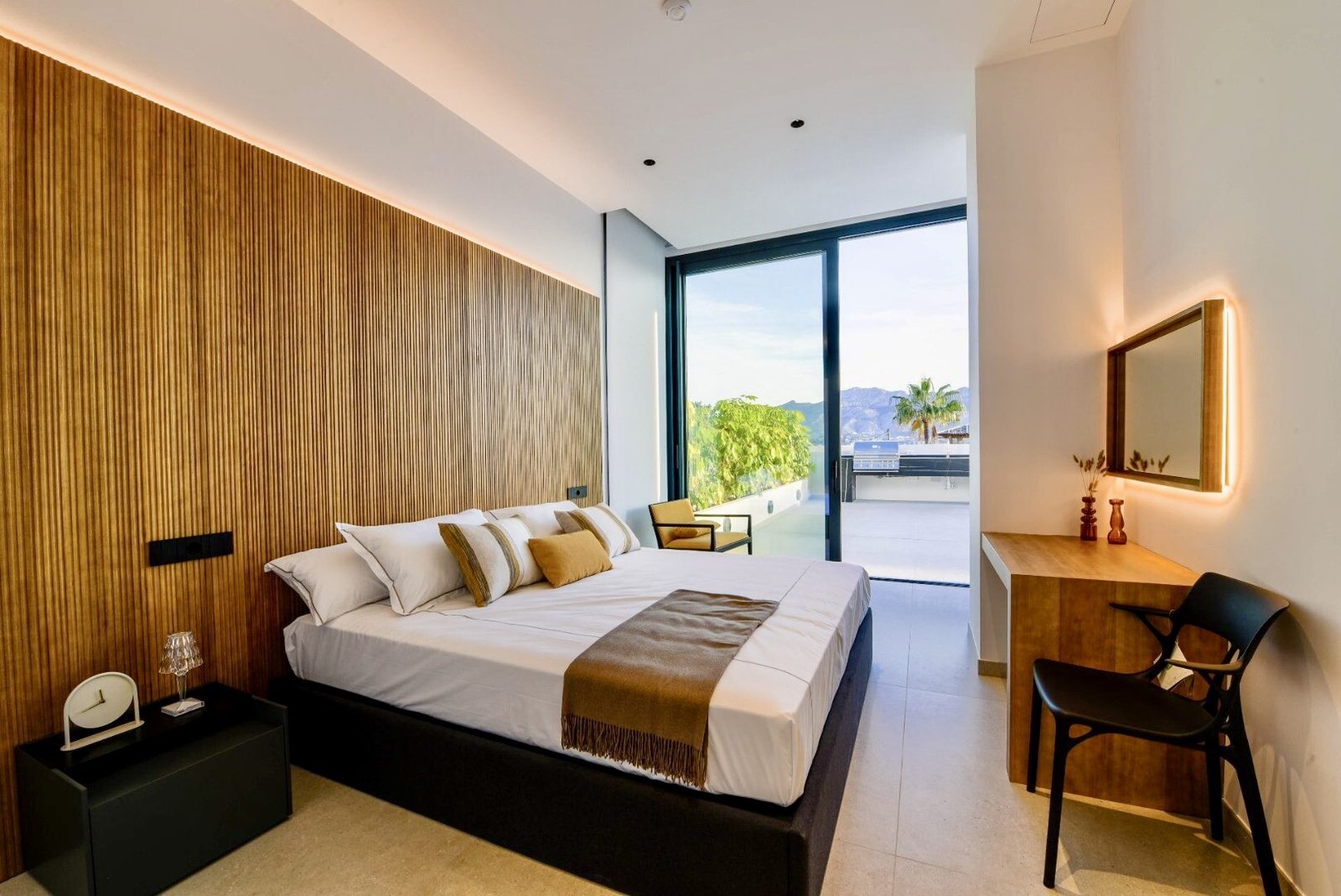A stylish bedroom with a view of lush greenery and the sea in a 4-bedroom villa in La Nucia - The Estates