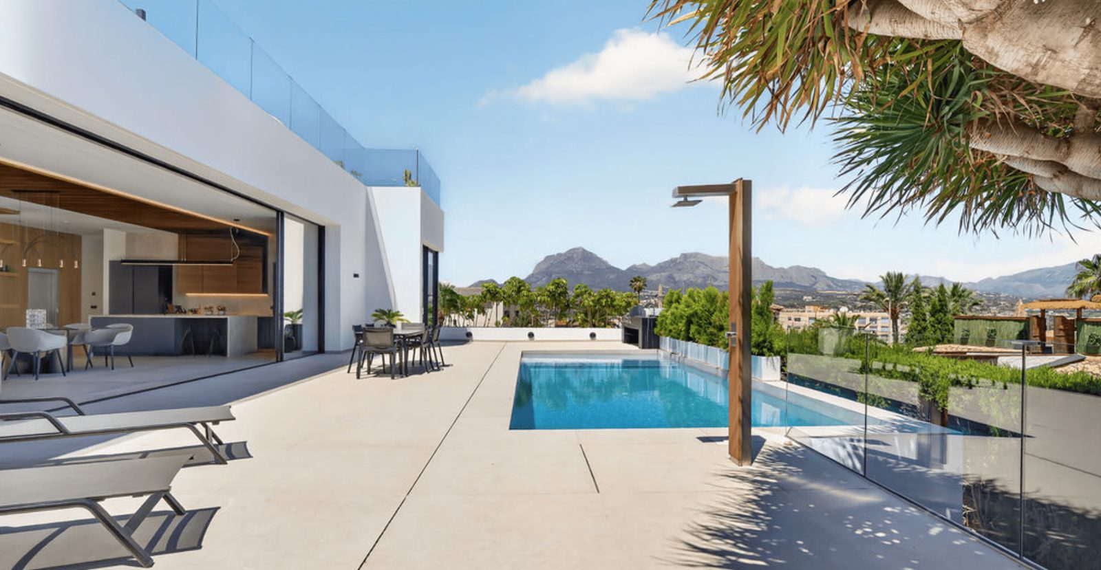 A modern terrace and pool area with stunning sea and city views of a 4-bedroom villa in La Nucia - The Estates