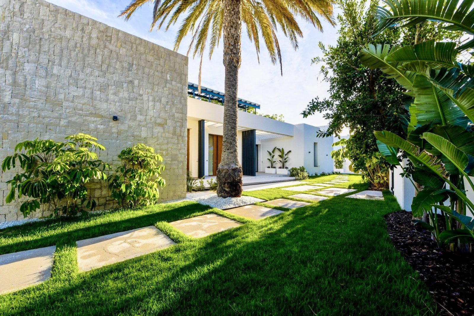 Lush garden path leading to a modern villa with palm trees in La Nucia - The Estates