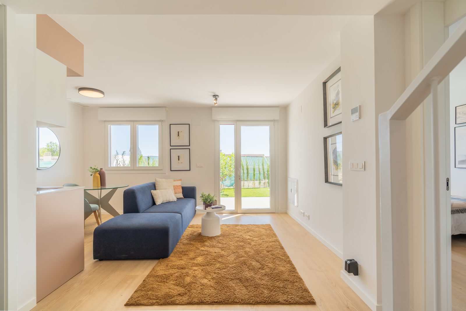 A bright living room with a sofa and patio doors overlooking greenery of a 4-bedroom townhouse in La Nucía - The Estates