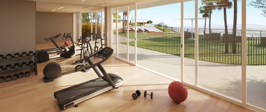 Home gym with treadmills and weights overlooking the garden and sea of a 4-bedroom villa in Finestrat - The Estates