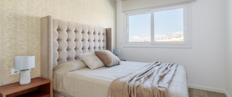Bright double bedroom with upholstered headboard, bedside tables and window views in a 4-bedroom villa in Finestrat - The Estates