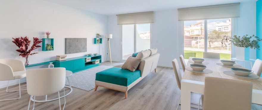 Bright open-plan living and dining room with turquoise furnishings and garden views in a 4-bedroom villa in Finestrat - The Estates