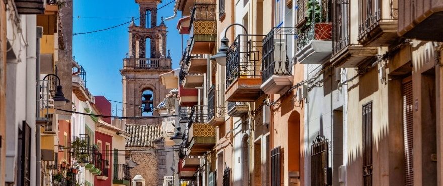 Historic Finestrat street with traditional balconies and a church tower, near a 4-bedroom villa in Finestrat - The Estates