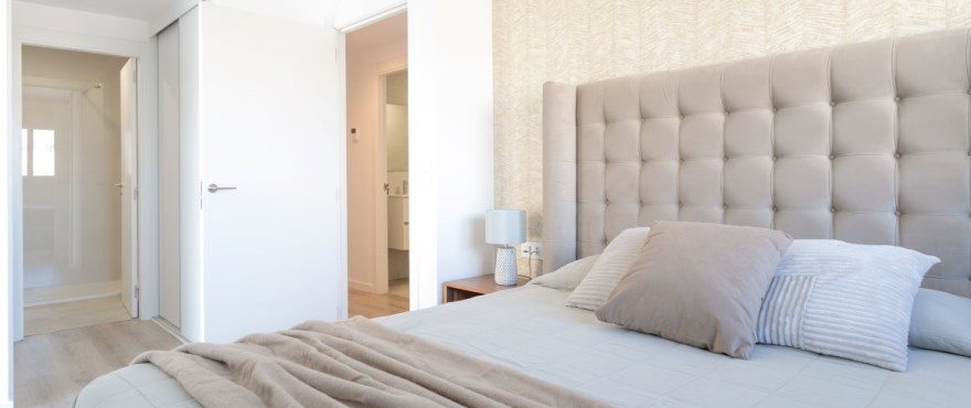 Bright bedroom with a tufted upholstered headboard, double bed and open doors of a 4-bedroom villa in Finestrat - The Estates