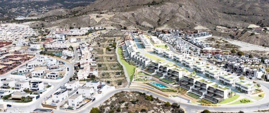 Aerial view of a modern villa development amid mountains in Finestrat, showing a 4-bedroom villa setting - The Estates