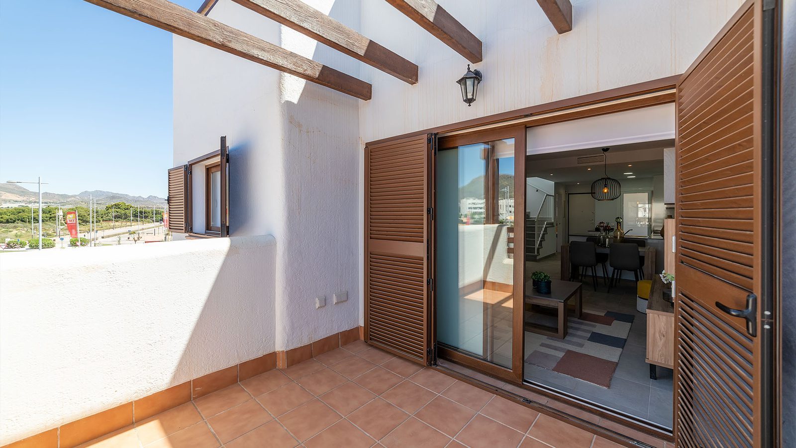 Covered terrace with wooden shutters and open doors to the living area of a 2-bedroom bungalow in Pulpí - The Estates