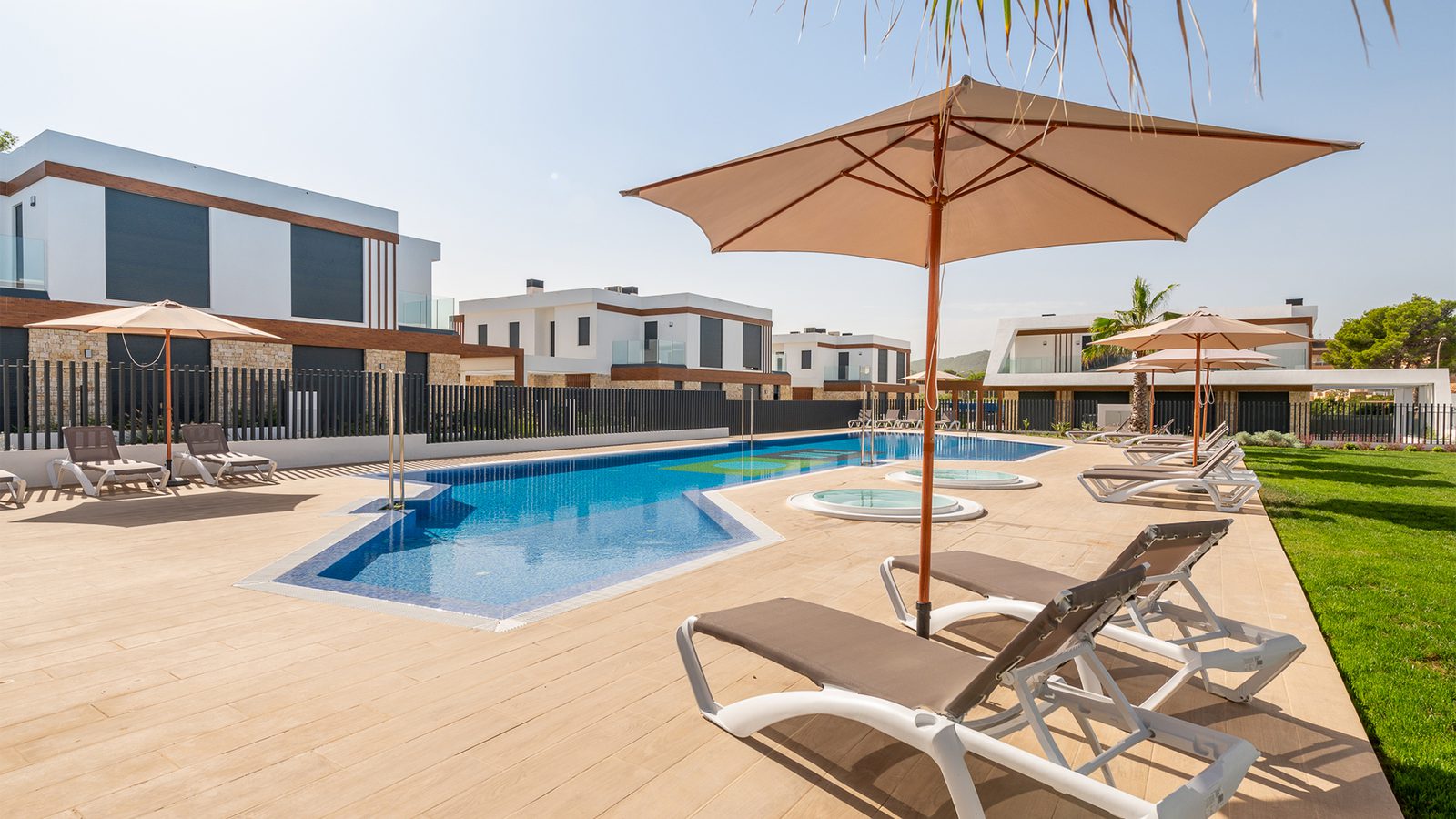 A sunny pool area with lounge chairs and umbrellas at a 3-bedroom semi-detached in Capdepera - The Estates