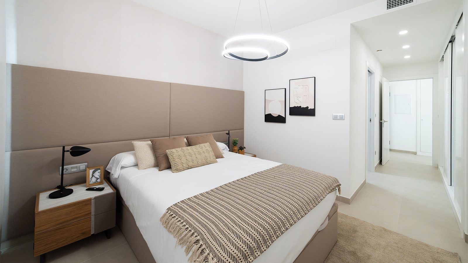 Modern master bedroom with upholstered headboard, double bed and hallway access in a 3-bedroom apartment in Benidorm - The Estates