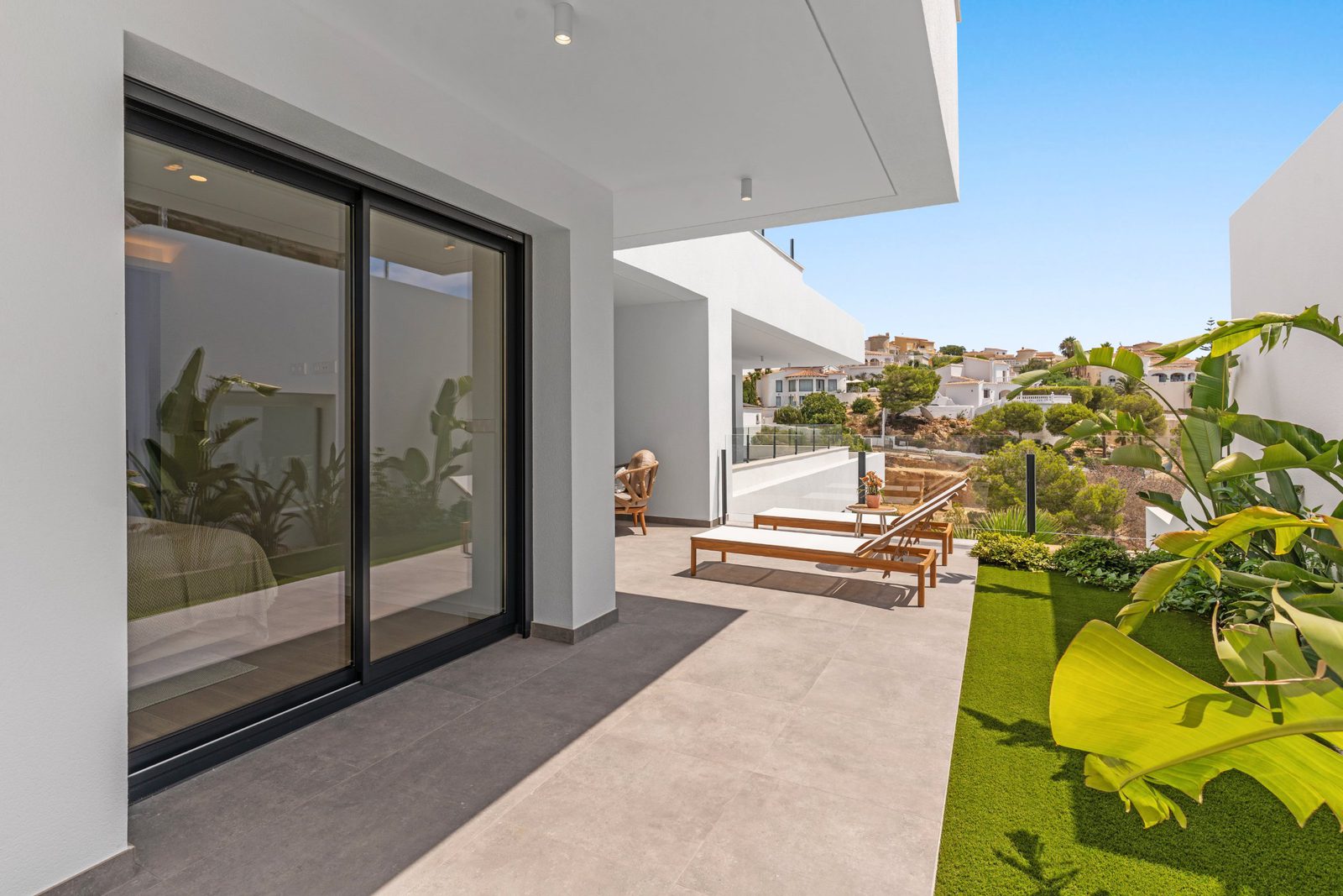 A modern balcony with lounge chairs and views of the surrounding landscape of a 3-bedroom apartment in Benitachell - The Estates