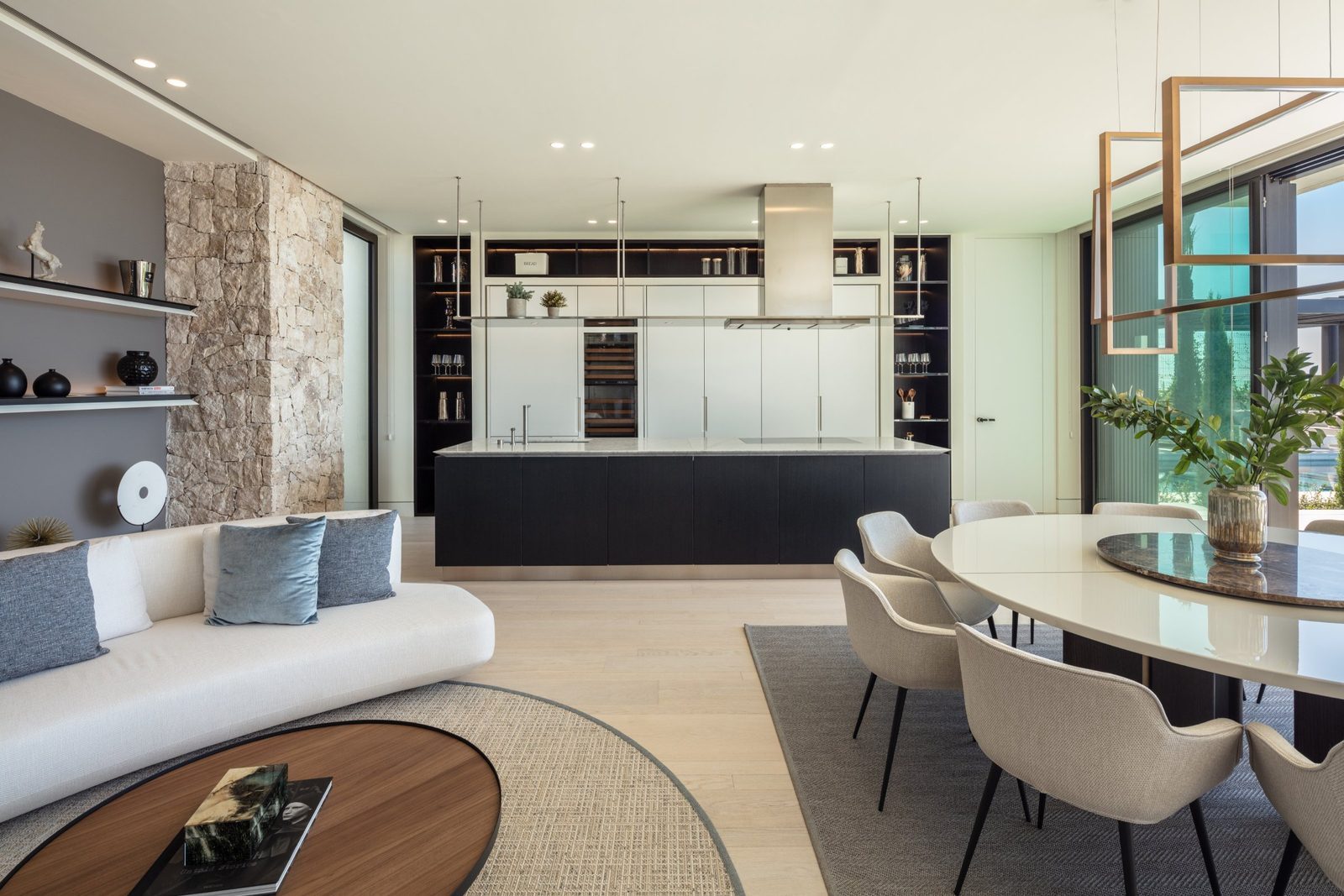 Open-plan kitchen, dining area and living room with stone accent wall and sea views in a 7-bedroom villa in Málaga - The Estates