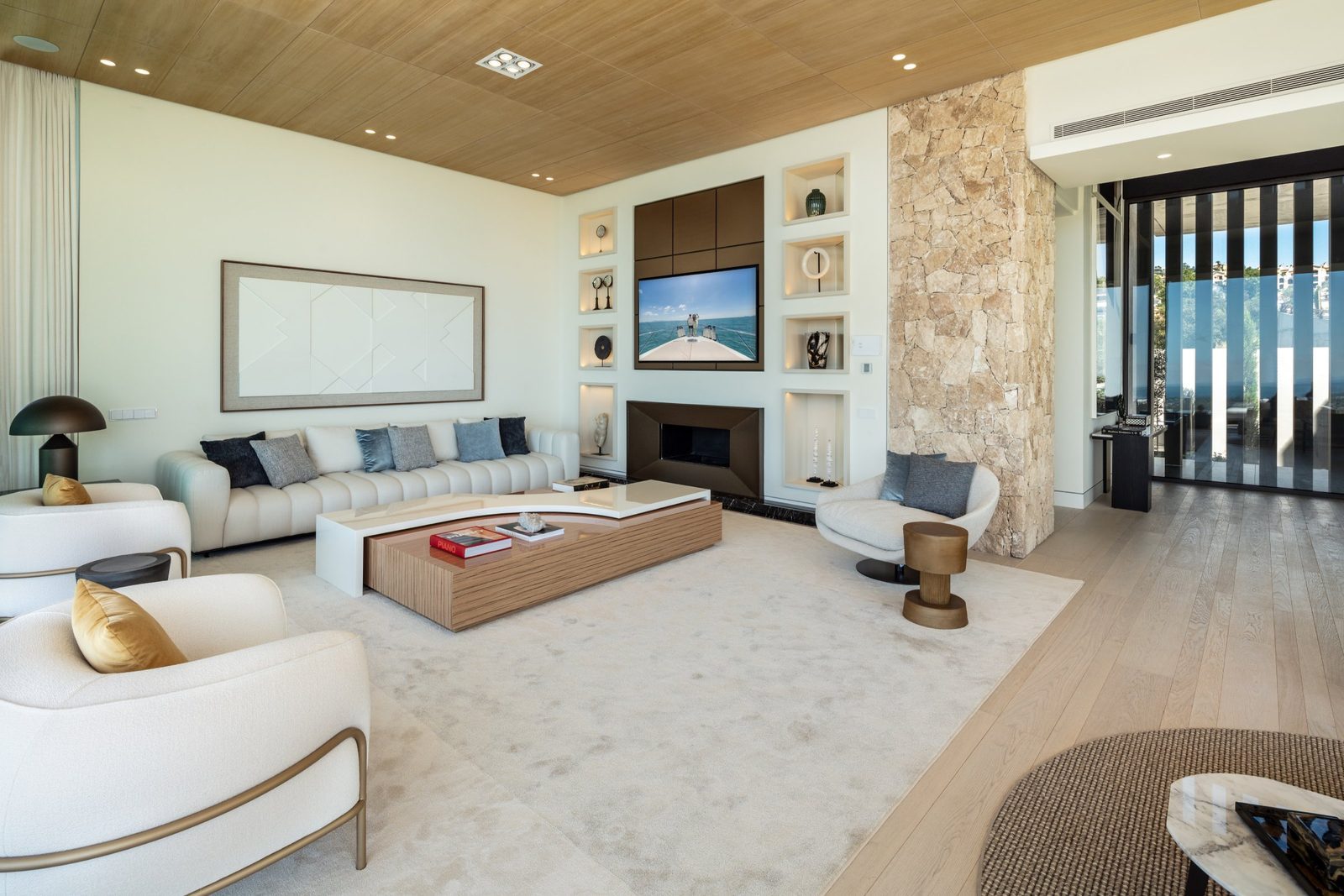 Contemporary living room with fireplace, designer seating, stone feature wall and sea views in a 7-bedroom villa in Málaga - The Estates
