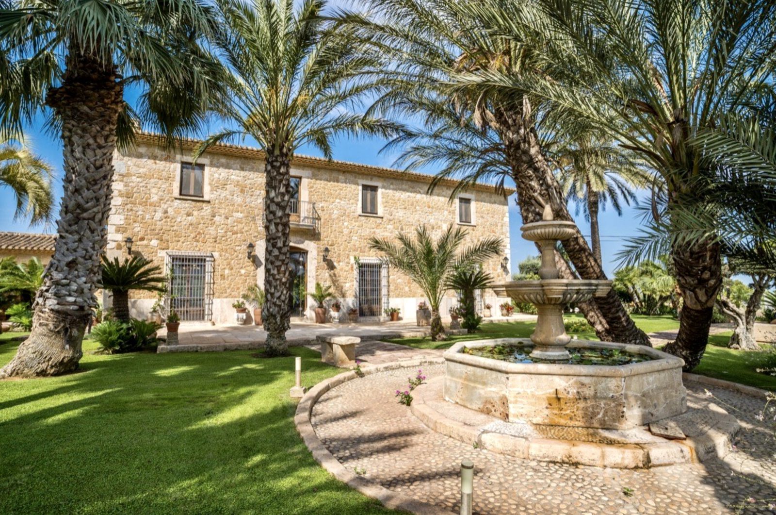 A beautiful stone finca with palm trees and a fountain in the garden - The Estates