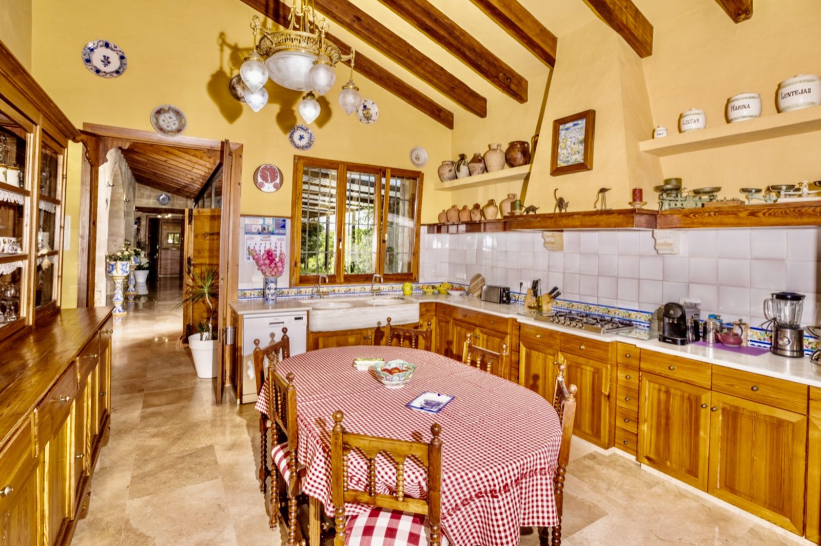 A bright, rustic kitchen with wooden beams and tiled floors in a 7-bedroom finca in Denia - The Estates