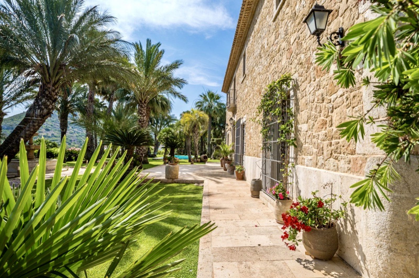 Exterior view of a stone finca with palm trees and a garden path in Denia - The Estates