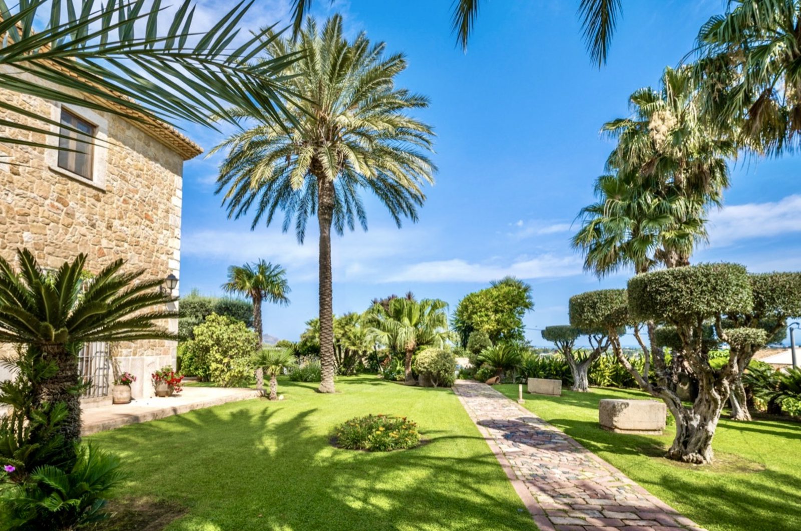 Lush garden and palm trees surrounding a stone finca in Denia - The Estates