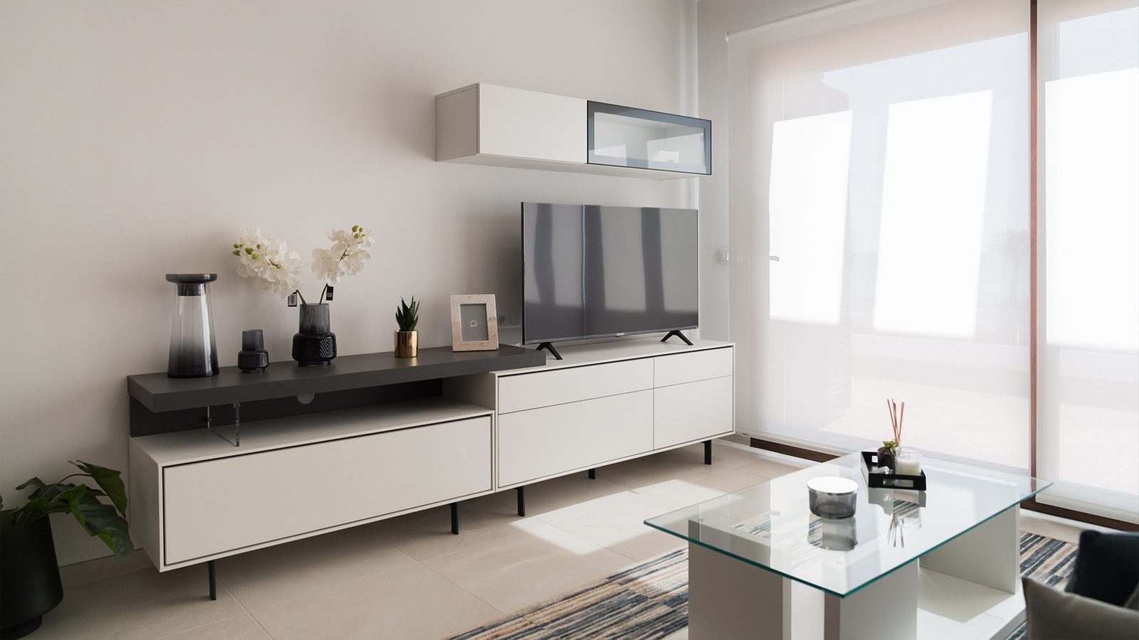 Bright modern living room with TV, stylish storage, glass coffee table and large windows in a 2-bedroom bungalow in Pulpí - The Estates