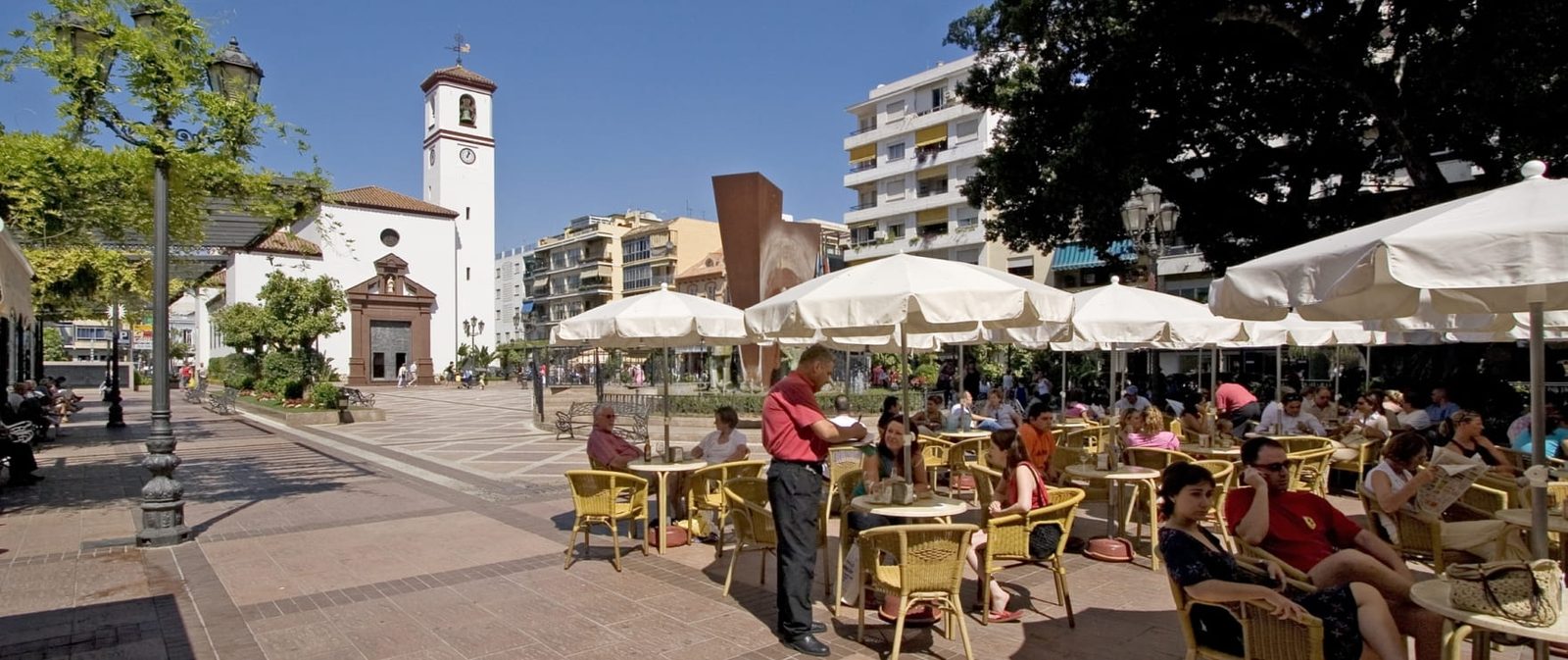 Town square with church, outdoor cafés and apartment buildings of a 2-bedroom apartment in Las Lagunas de Mijas - The Estates
