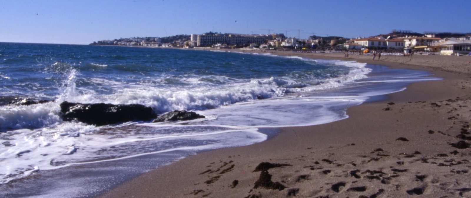 Coastal beach with waves and beachfront buildings near a 2-bedroom apartment in Las