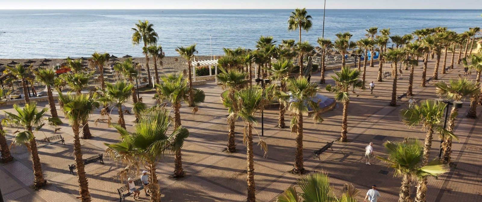 Sea view over a palm-lined beachfront promenade of a 2-bedroom apartment in Las Lagunas de Mijas - The Estates