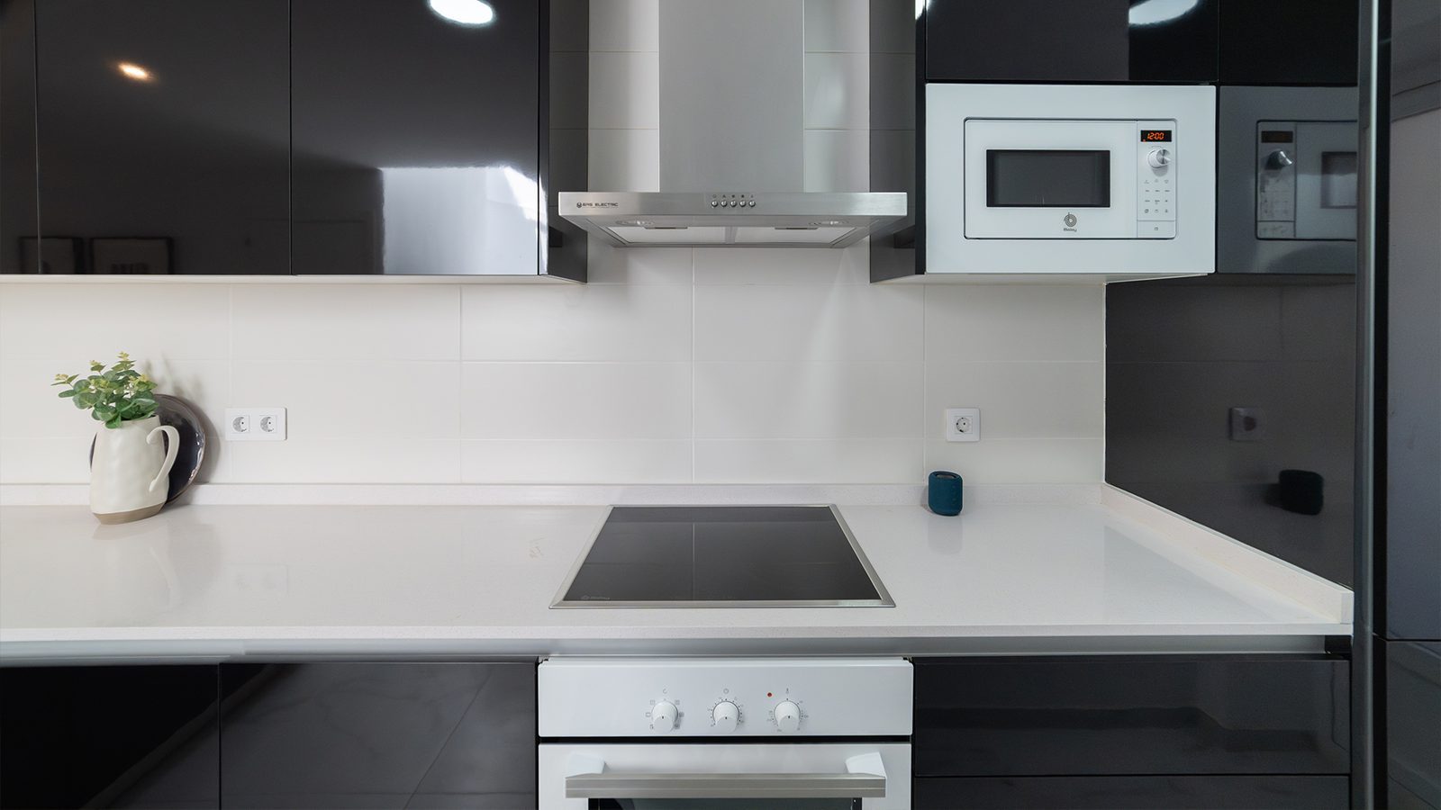 Modern black and white kitchen with induction hob, oven, microwave and extractor hood in a 2-bedroom bungalow in Pulpí - The Estates