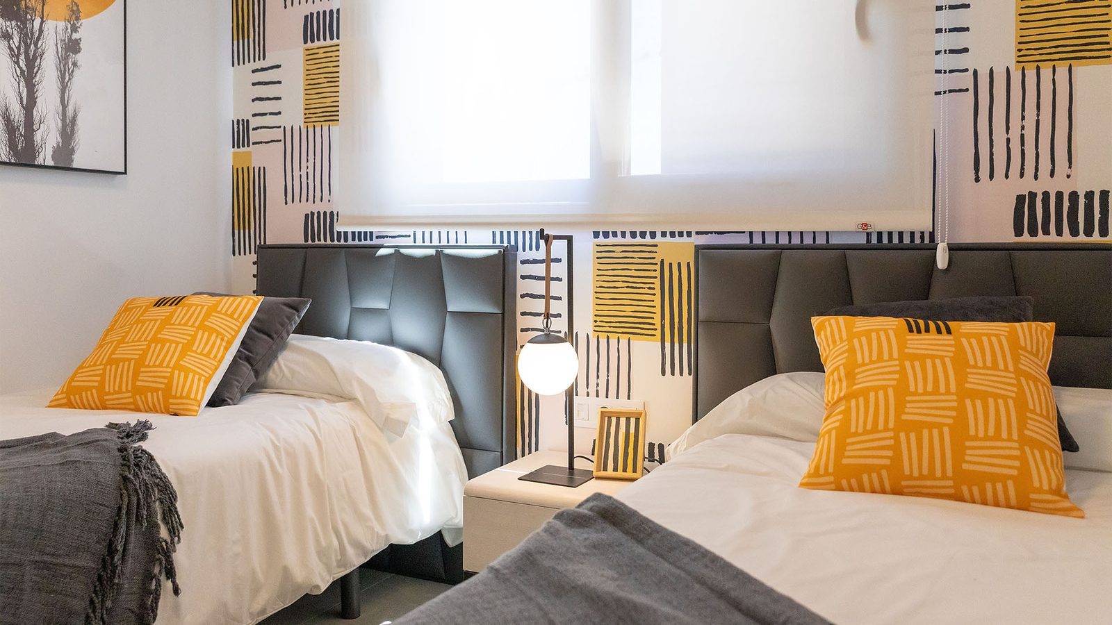 Twin bedroom with patterned yellow and black wallpaper, two beds and a bedside lamp in a 3-bedroom bungalow in Pulpí - The Estates