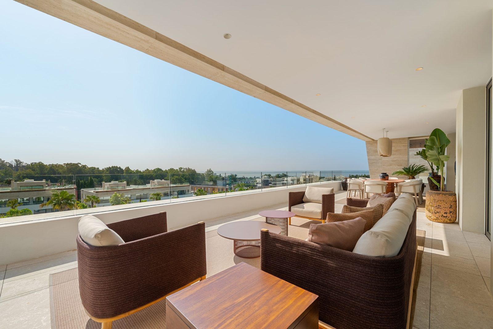 Covered terrace with lounge seating, dining area and sea views of a 4-bedroom penthouse in Málaga - The Estates
