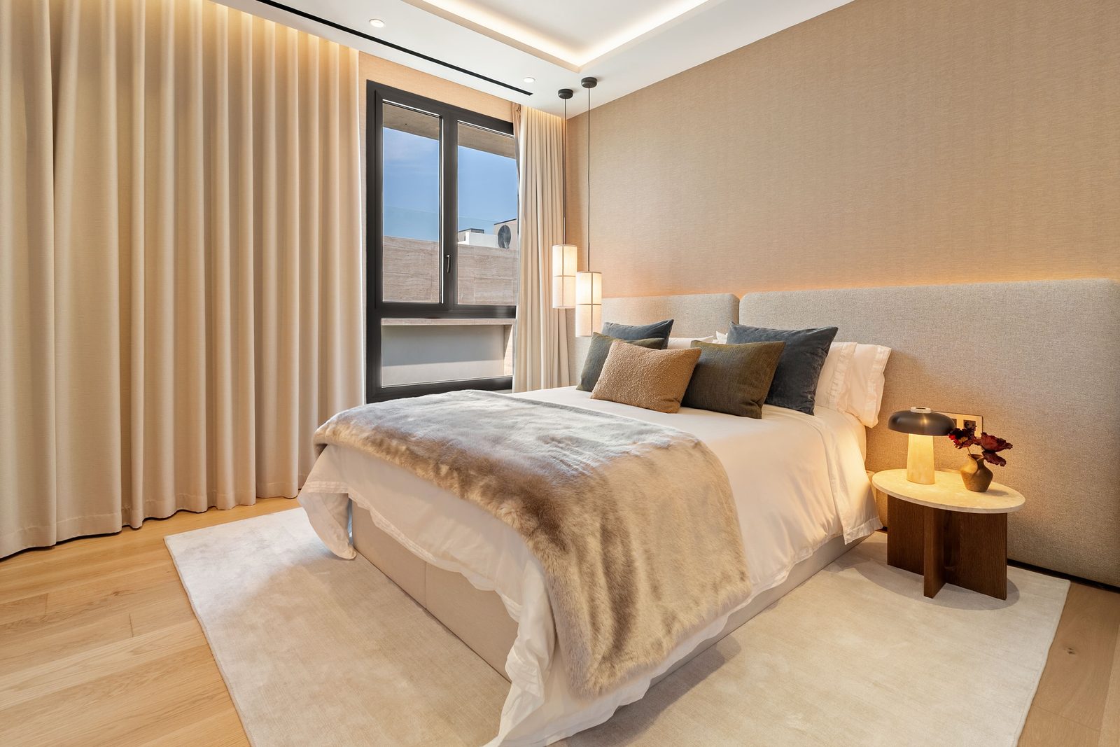 Elegant bedroom with upholstered bed, layered bedding, ambient lighting and full-height curtains in a 4-bedroom penthouse in Málaga - The Estates
