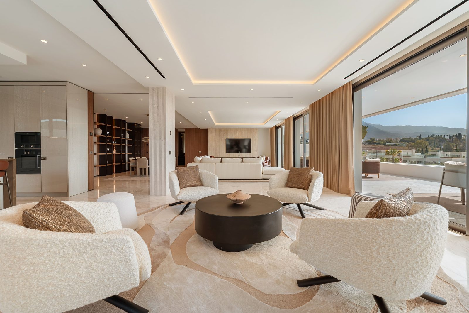 Open-plan living room with designer seating, kitchen and mountain views of a 4-bedroom penthouse in Málaga - The Estates