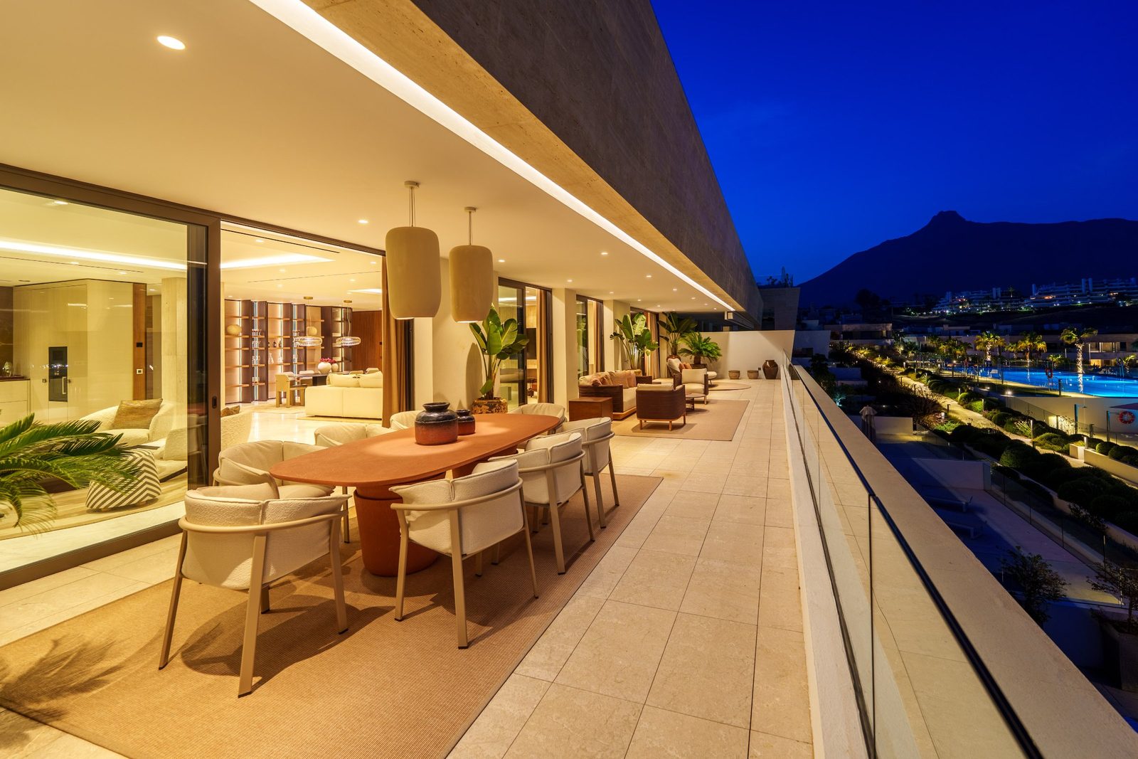 Covered terrace with outdoor dining and lounge overlooking pools and mountains of a 4-bedroom penthouse in Málaga - The Estates
