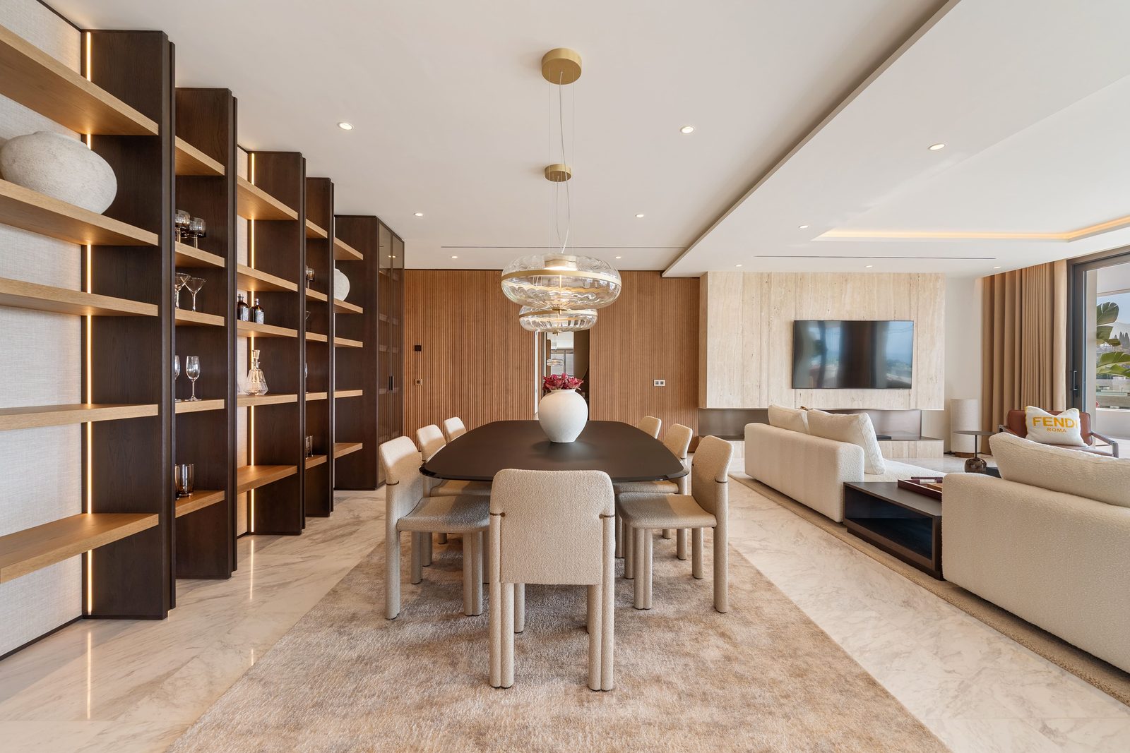 Elegant open-plan dining and living area with designer shelving, marble floors and sea views in a 4-bedroom penthouse in Málaga - The Estates