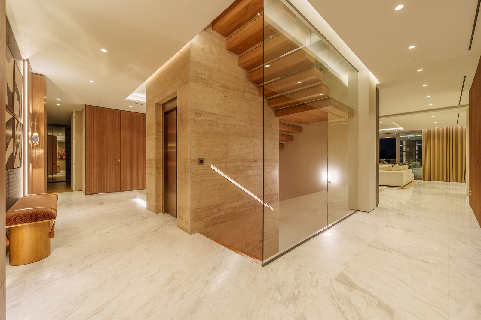 Marble entrance hall with glass staircase, elevator and wood accents in a 4-bedroom penthouse in Málaga - The Estates