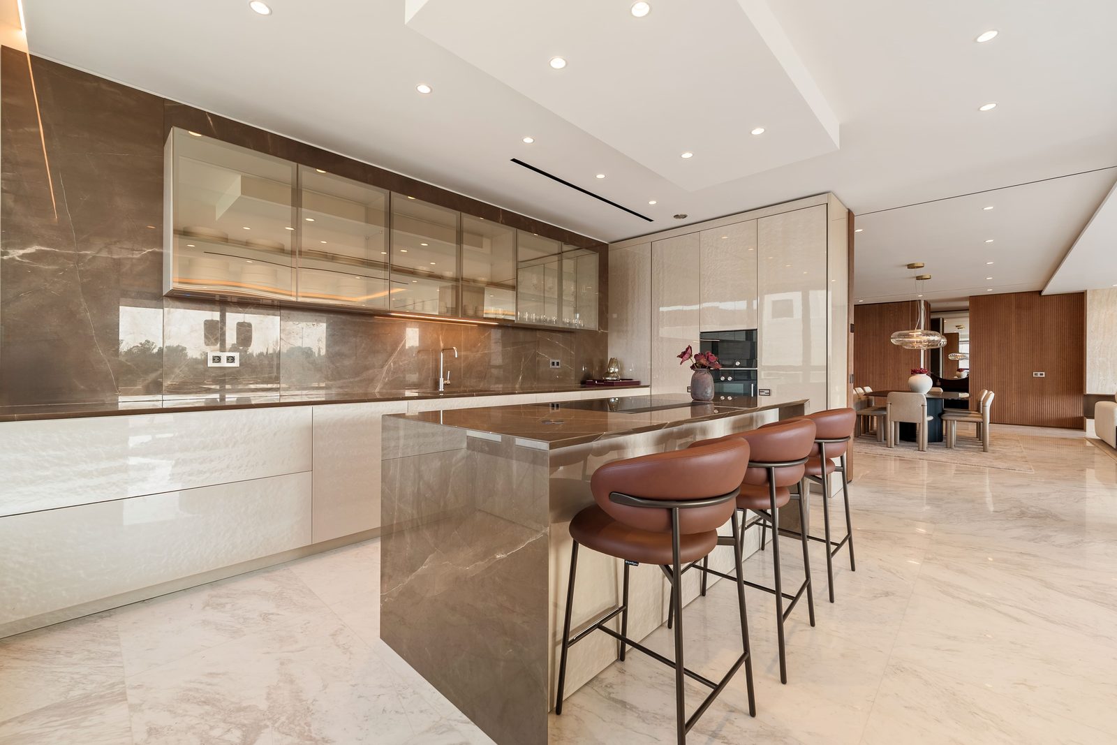 Modern marble kitchen with island and bar stools in a 4-bedroom penthouse in Málaga - The Estates