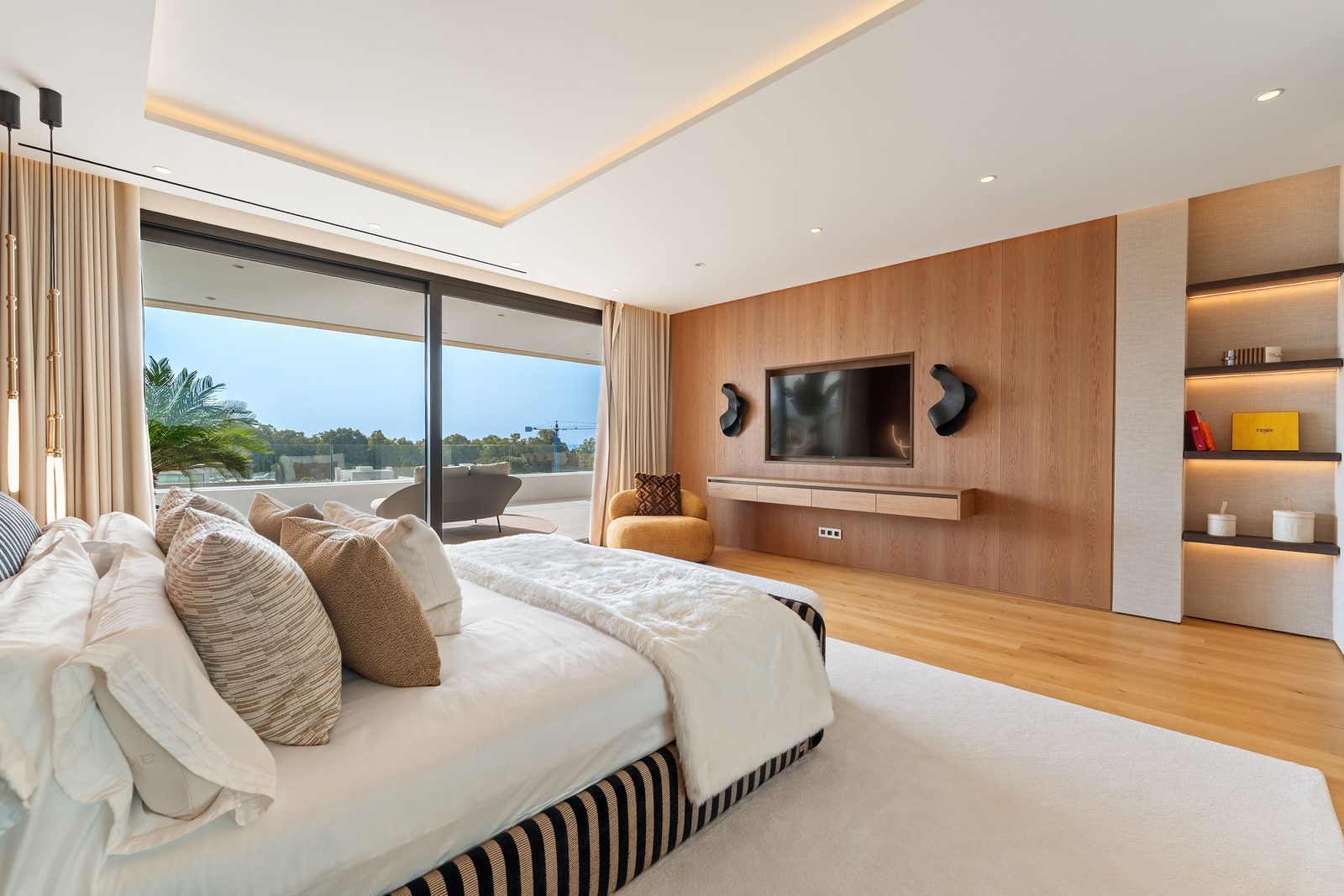 Modern bedroom with TV wall, built-in shelving and terrace views of a 4-bedroom penthouse in Málaga - The Estates