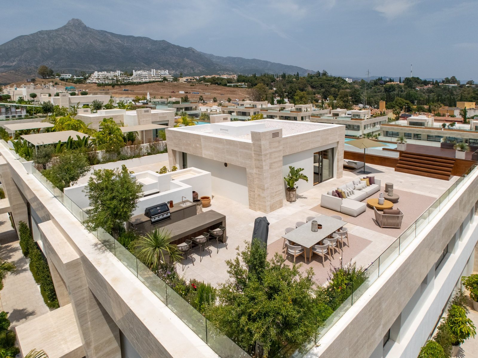 Rooftop terrace with outdoor kitchen, dining and lounge areas overlooking La Concha mountain, Marbella, of a 4-bedroom penthouse in Málaga - The Estates
