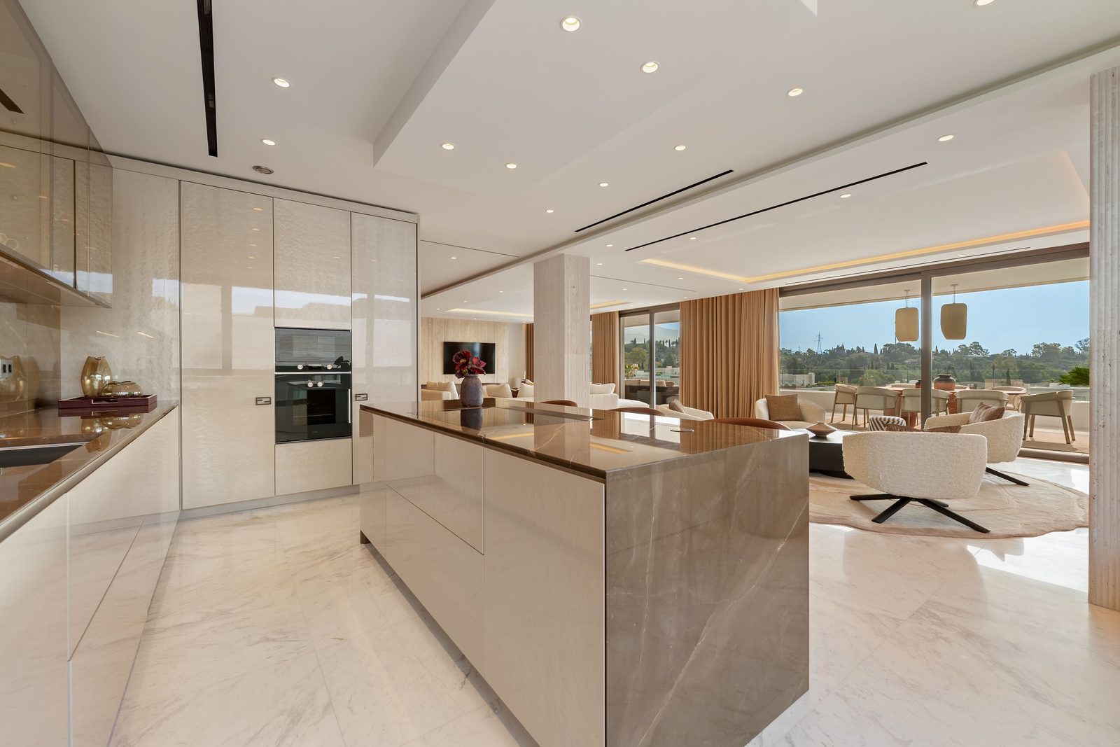 Modern open-plan kitchen and living area with marble island and terrace views in a 4-bedroom penthouse in Málaga - The Estates