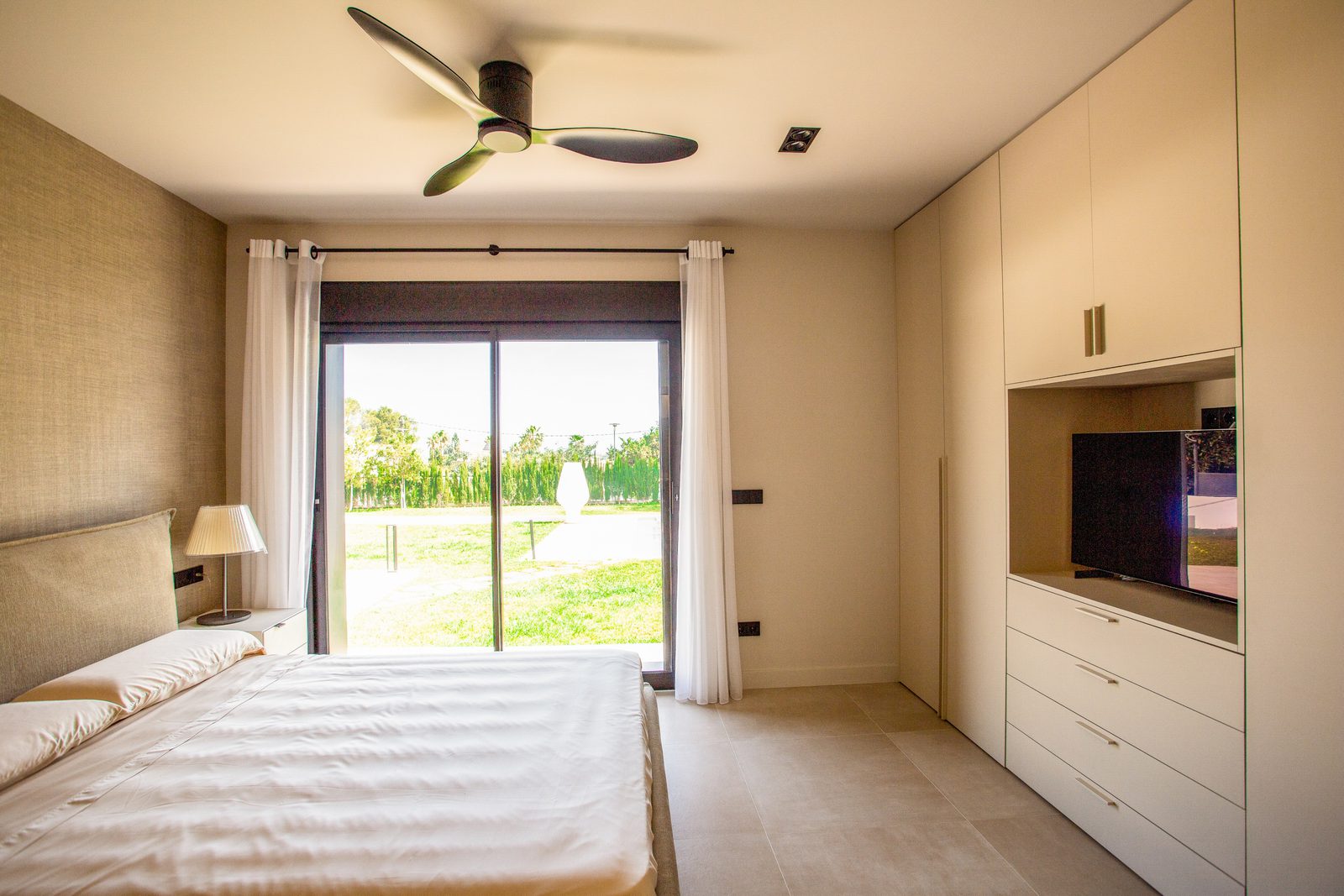A bright bedroom with built-in wardrobes and patio doors overlooking the countryside in a 3-bedroom villa in Denia - The Estates