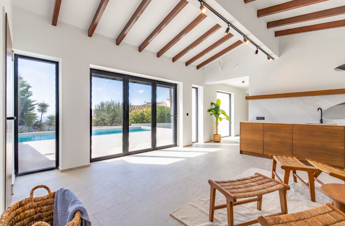Bright living area with exposed beams and patio doors leading to a pool in a 5-bedroom villa in Benitachell - The Estates