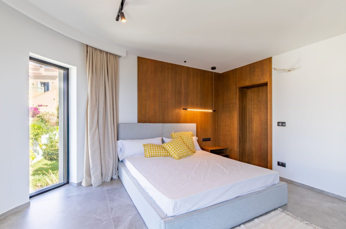 A modern bedroom with large windows and wood paneling in a 5-bedroom villa in Benitachell - The Estates