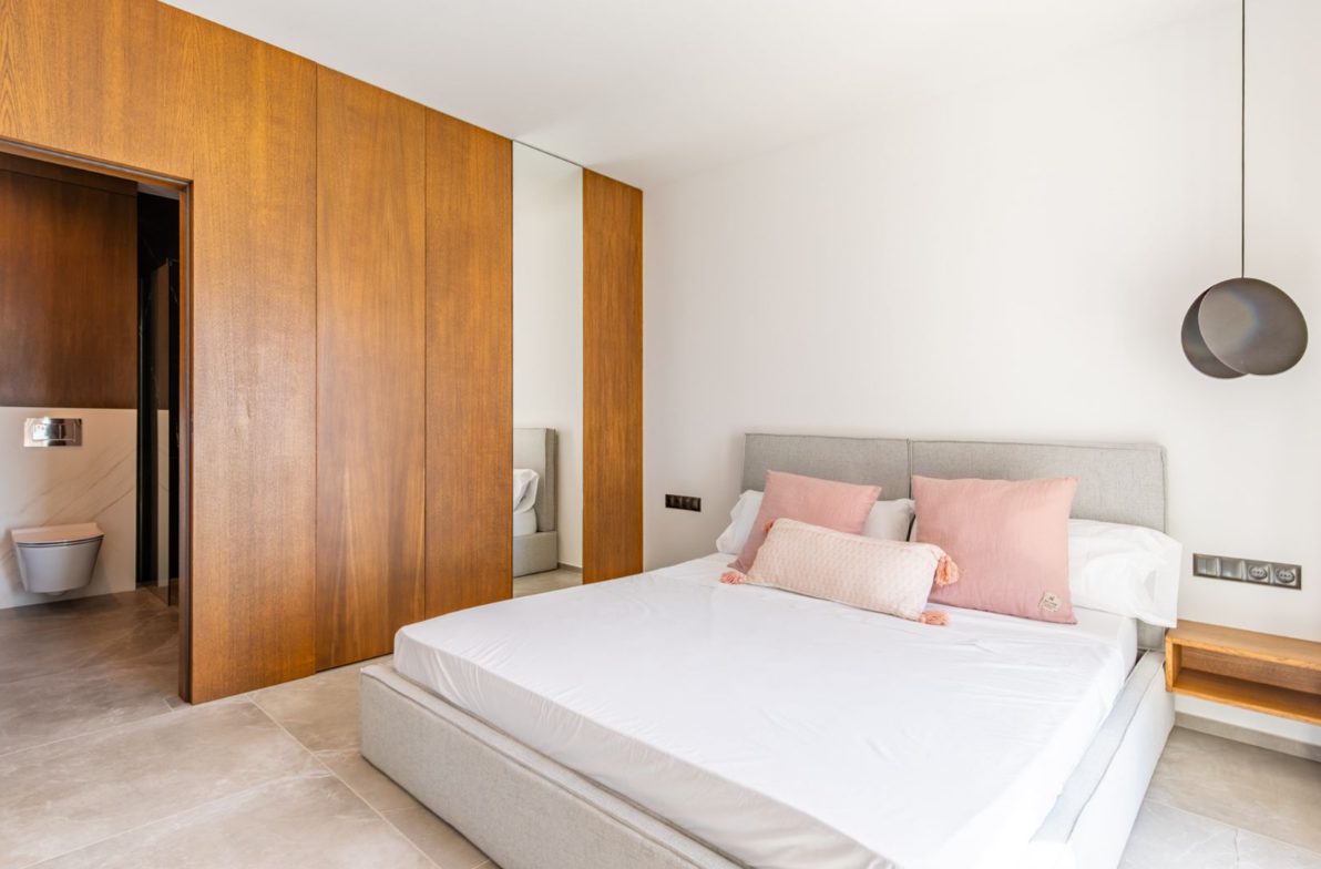 A modern bedroom with wood paneling and a comfortable bed in a 5-bedroom villa in Benitachell - The Estates