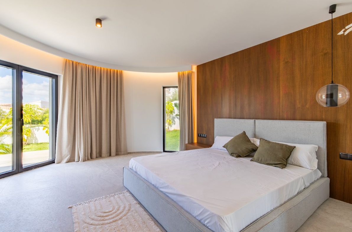 A stylish bedroom with large windows and wood paneling in a 5-bedroom villa in Benitachell - The Estates