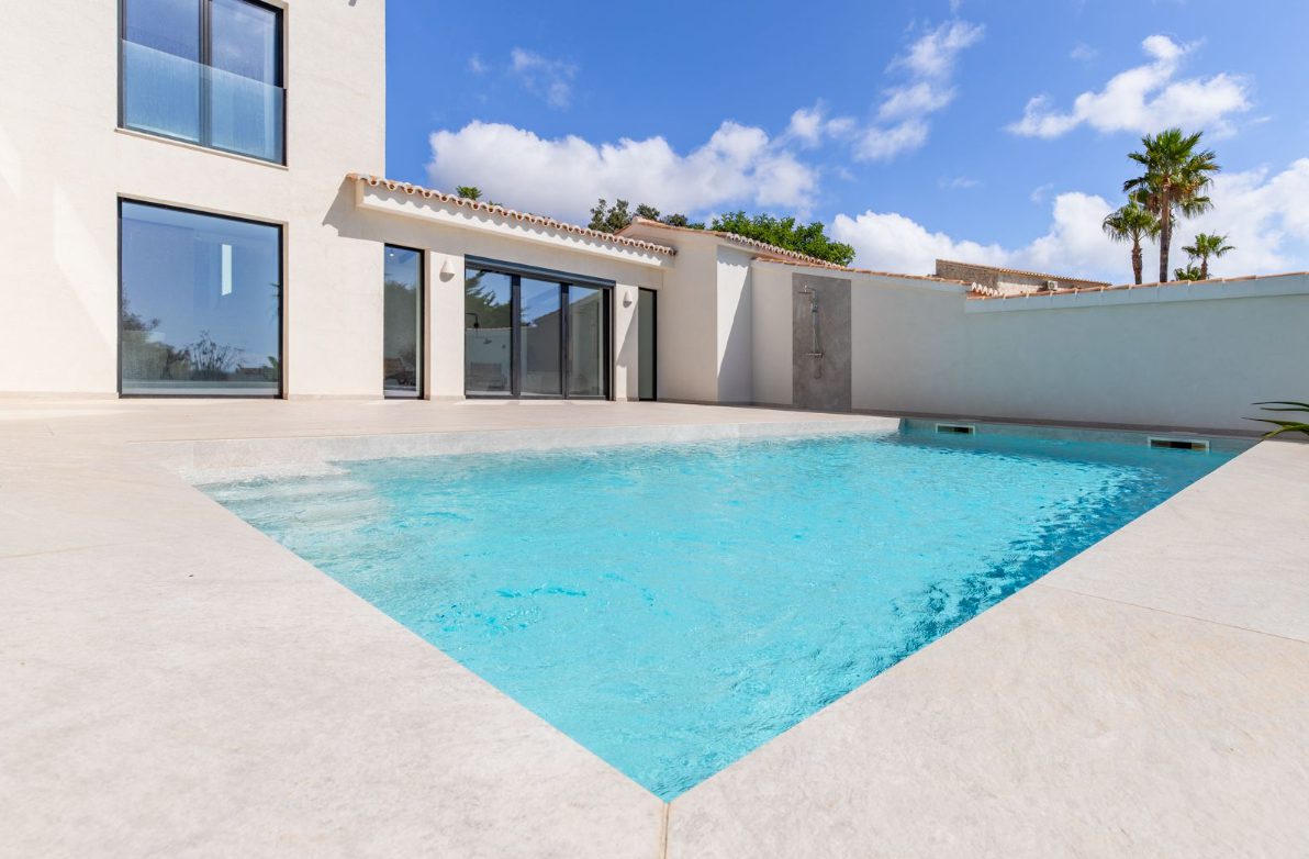 A modern pool area with a villa in the background of a 5-bedroom villa in Benitachell - The Estates