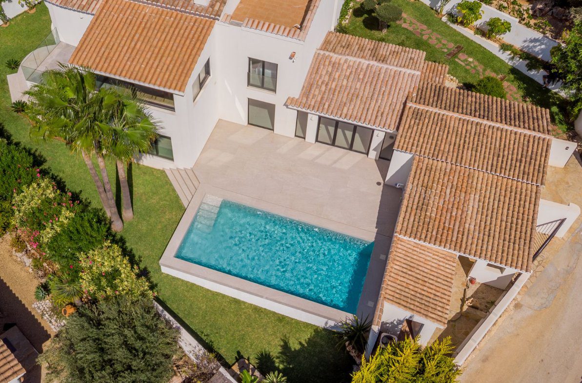 Aerial view of a luxurious villa with a pool and garden in Benitachell - The Estates