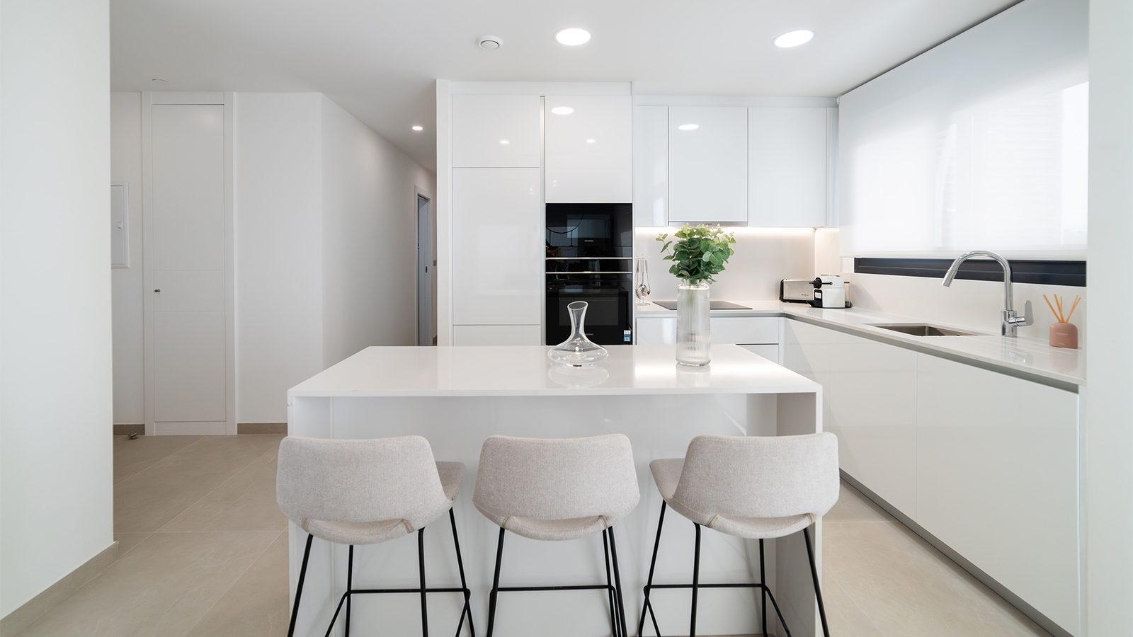 Modern white kitchen with island breakfast bar in a 2-bedroom apartment in Benidorm - The Estates