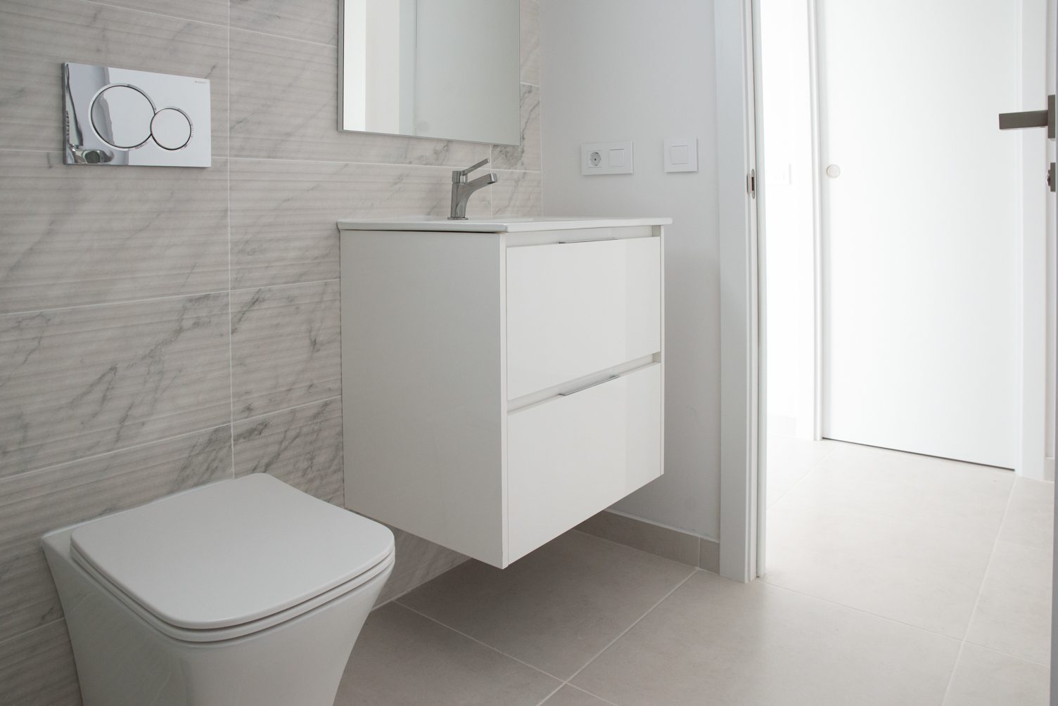 Modern bathroom with wall-hung toilet, white vanity and marble-effect tiles in a 3-bedroom villa in Busot, zona Bonalba Golf - The Estates