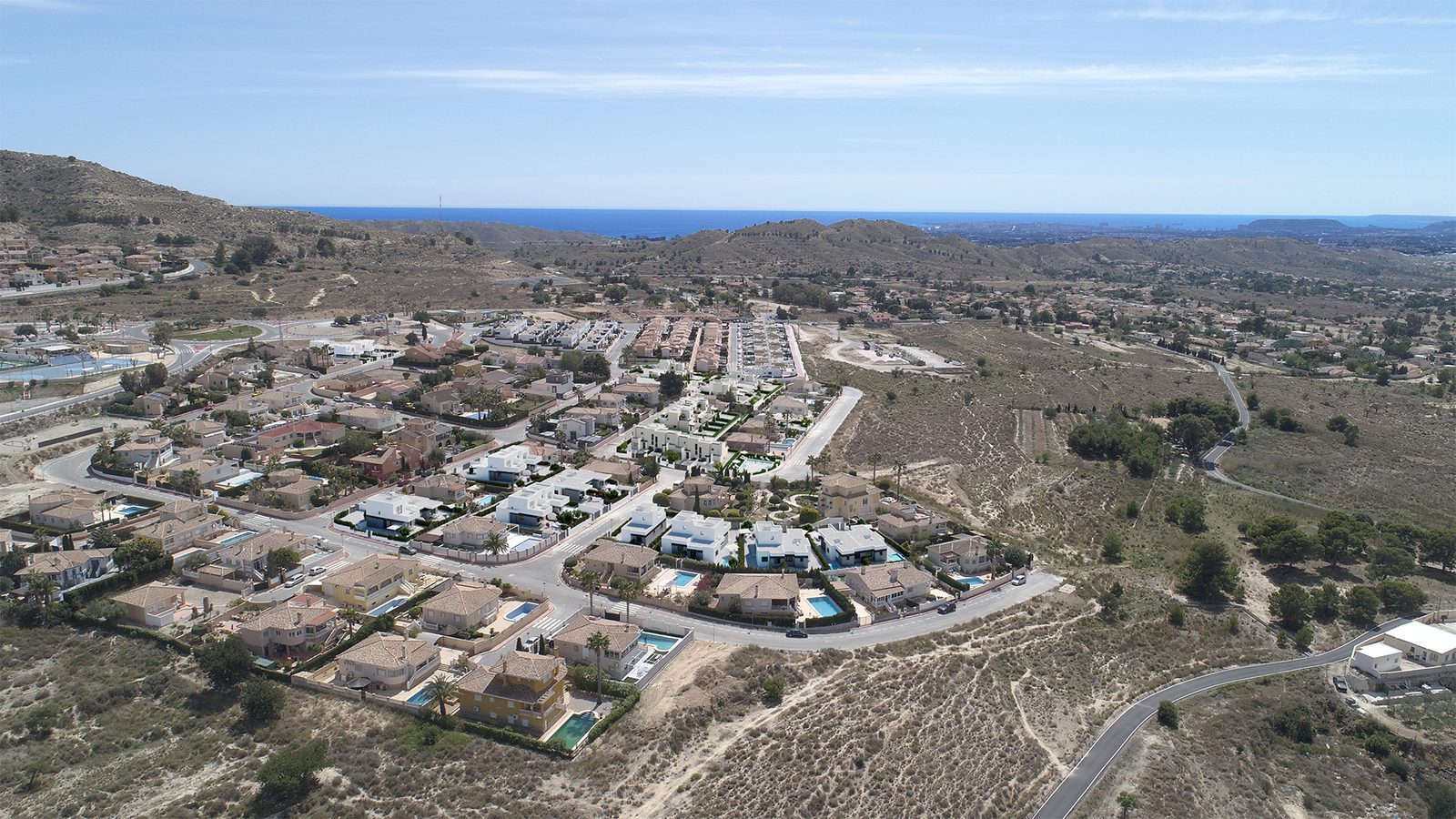 Aerial view of villas, mountains and coastline near a 3-bedroom villa in Busot, zona Bonalba Golf - The Estates