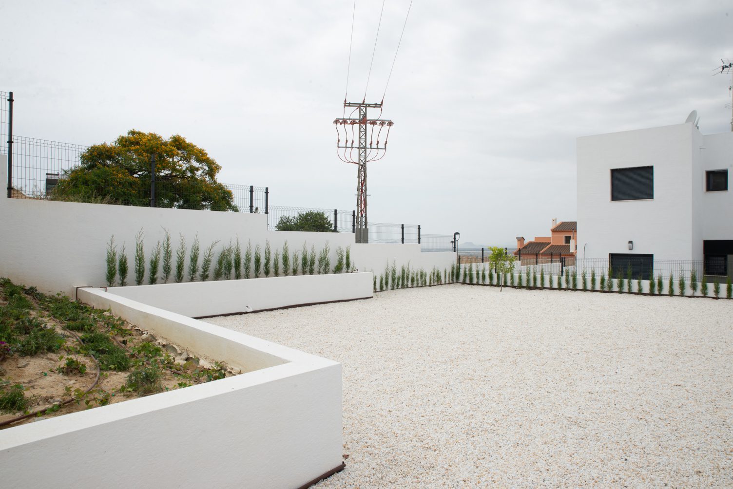 White villa exterior with a landscaped gravel courtyard and raised planting beds, with mountain views, of a 3-bedroom villa